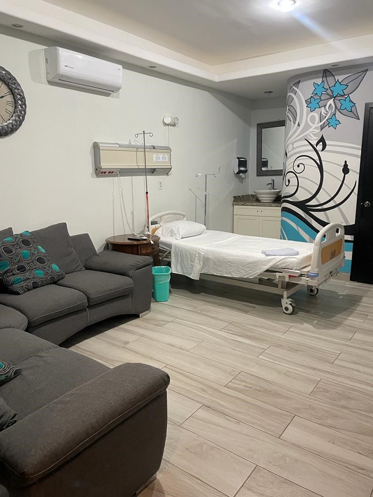 Private recovery room with a hospital bed and seating area at our clinic in Rocky Point, MX